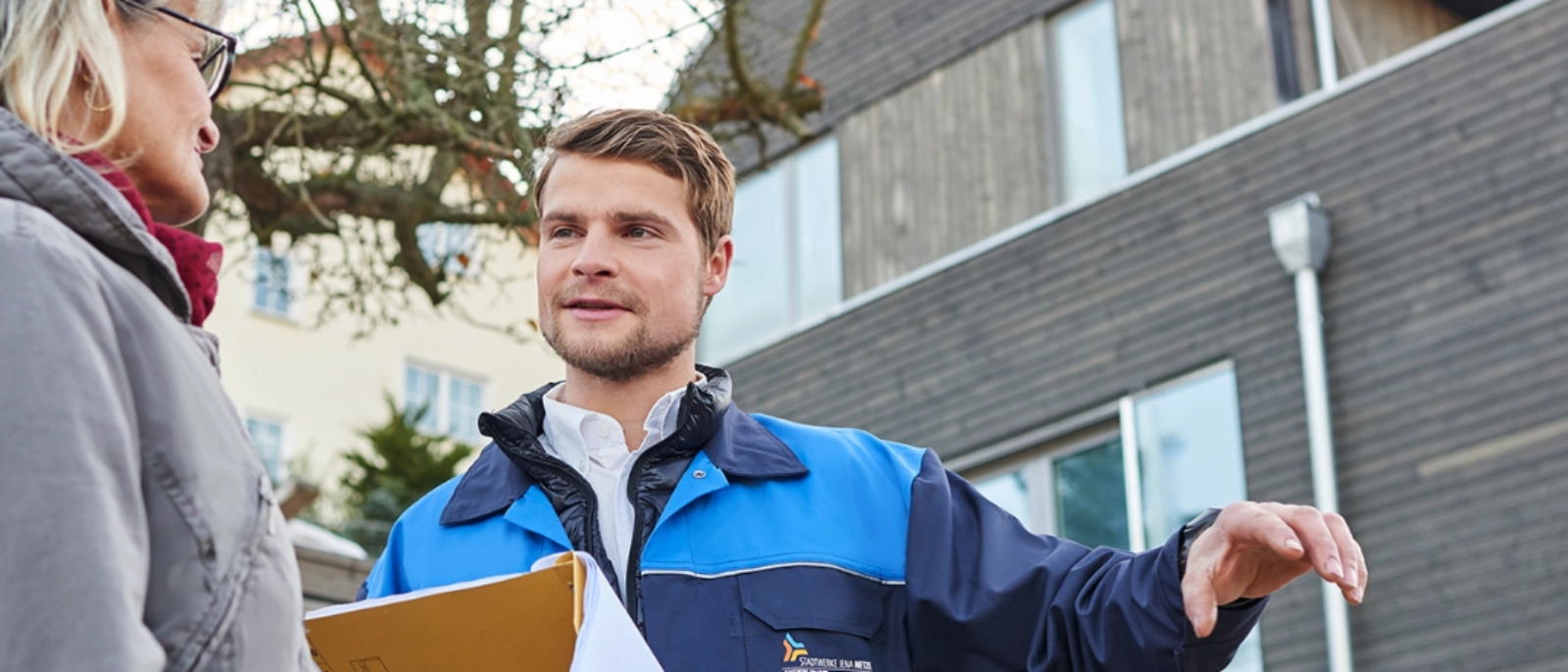 Mitarbeiter der Stadwerke Jena Netze vor einem Haus im Gespräch mit einer Frau