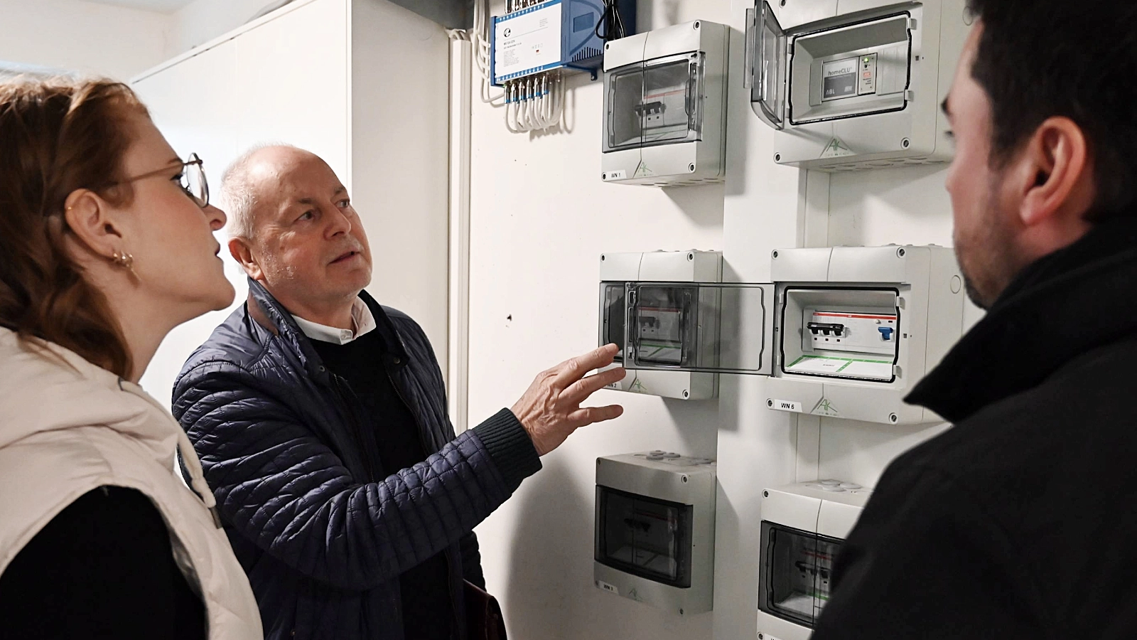 Dennis Beyermann und Djamila Neutert von den Stadtwerken werfen bei der Übergabe mit Hausverwalter Rainer Raithel einen Blick auf die Stromzähler der Wallboxen und das dynamische Lastmanagement.  