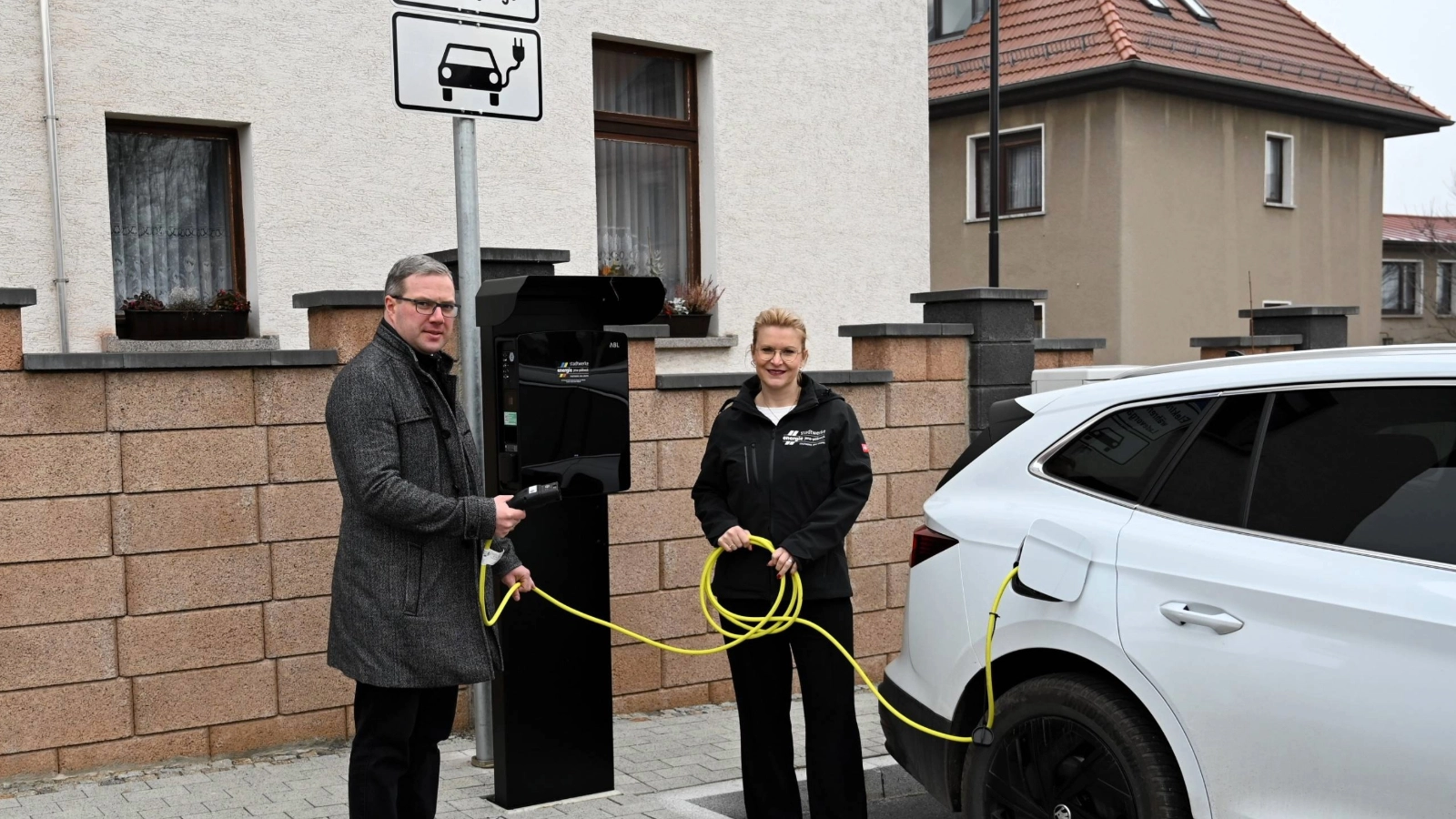 Hermsdorfs Bürgermeister Benny Hofmann und Djamila Neutert von den Stadtwerken Energie an den neuen Ladepunkten in der Hermsdorfer Schulstraße. 