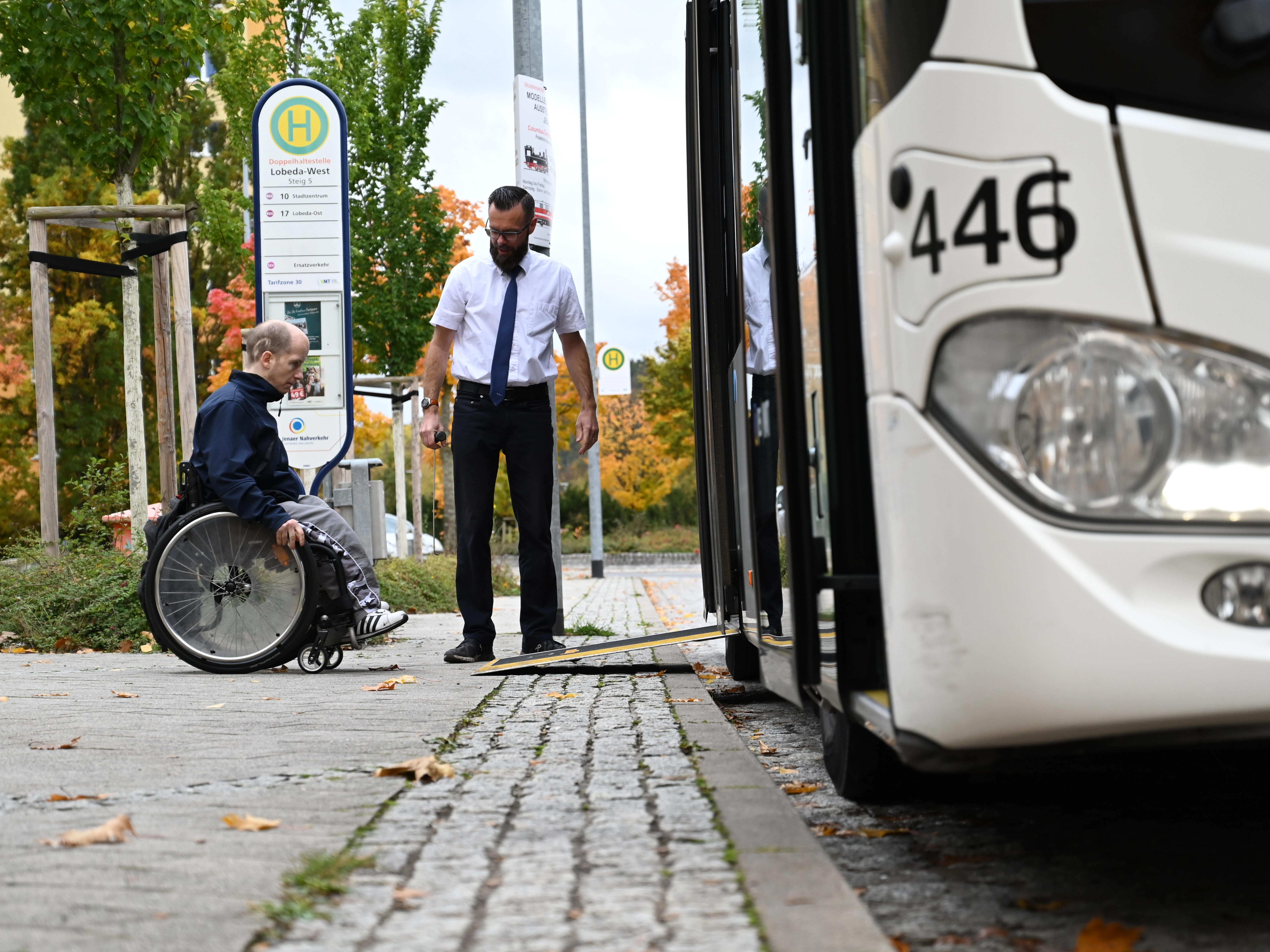 Ein Rollstuhlfahrer fährt in den Bus. Der Busfahrer steht daneben.